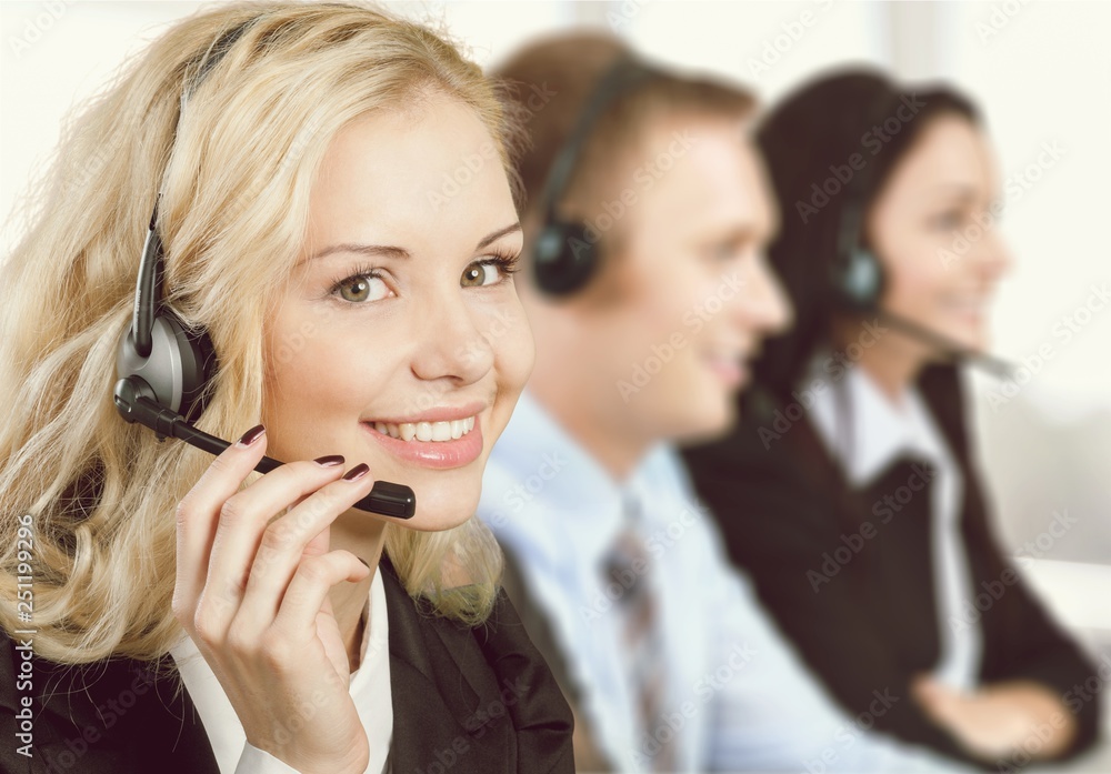Female call center employee with coworkers on background Female call center employee with coworkers on background