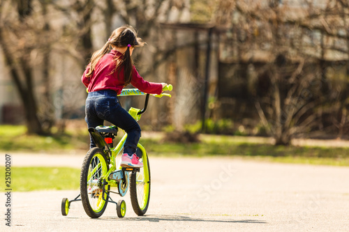Fototapeta Naklejka Na Ścianę i Meble -  Children riding on a bicycles at asphalt road in the park in summer