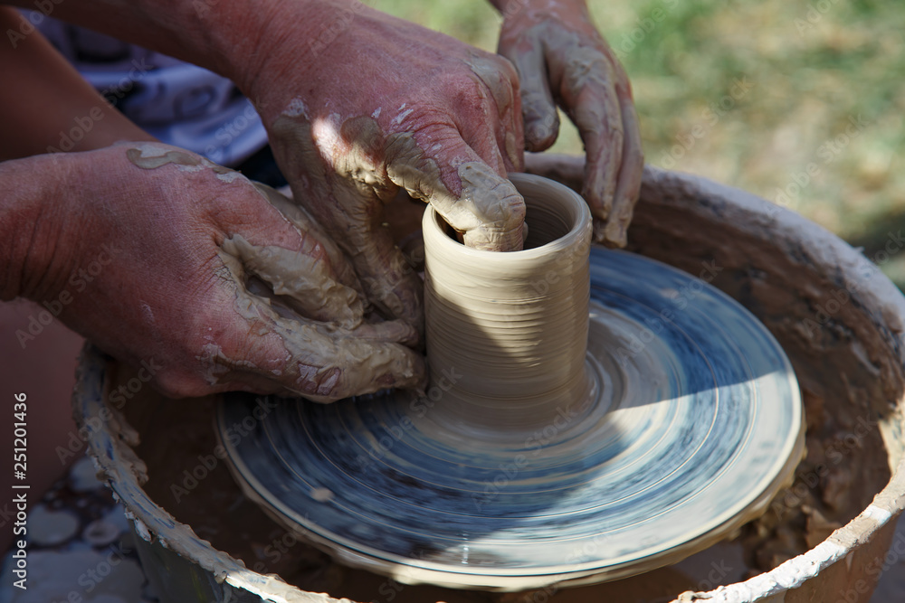 Hands of master  and apprentice on potter's wheel