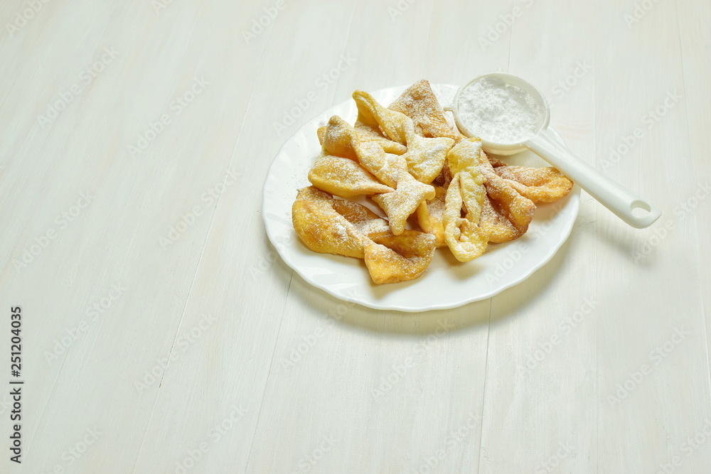 a plate full of angel wings sprinkled with powdered sugar a plate full of angel wings sprinkled with powdered sugar