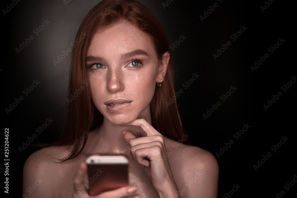 The portrait of a young redhead lady isolated over a black background The portrait of a young redhead lady isolated over a black background