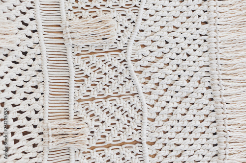 Detail of cream macrame decor displayed hanging on a wall.