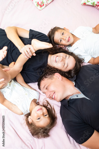 Family Values. Happy Caucasian Family of Four Having Fun While Lying on Sofa Indoors.
