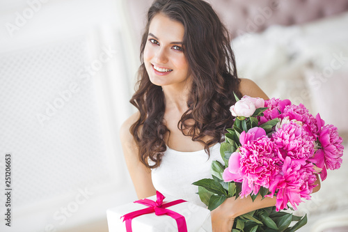 Very beautiful woman with peony and gift box indoors