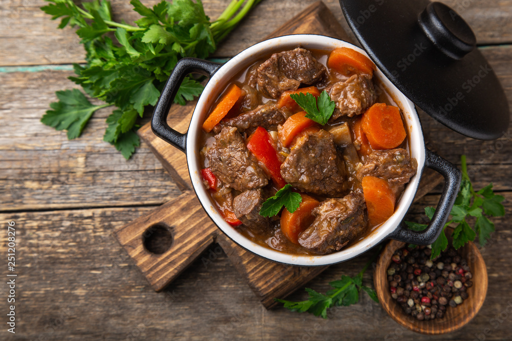 beef stew with vegetables in black pot on dark wooden background, beef stew with vegetables in black pot on dark wooden background,