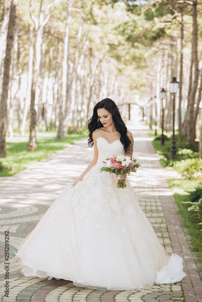 Beautiful bride in a white wedding dress on outdoors. Holding a wedding bouquet