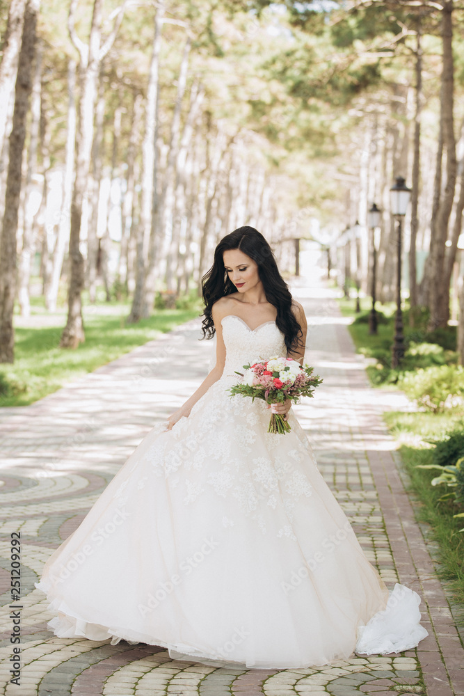 Beautiful bride in a white wedding dress on outdoors. Holding a wedding bouquet Beautiful bride in a white wedding dress on outdoors. Holding a wedding bouquet