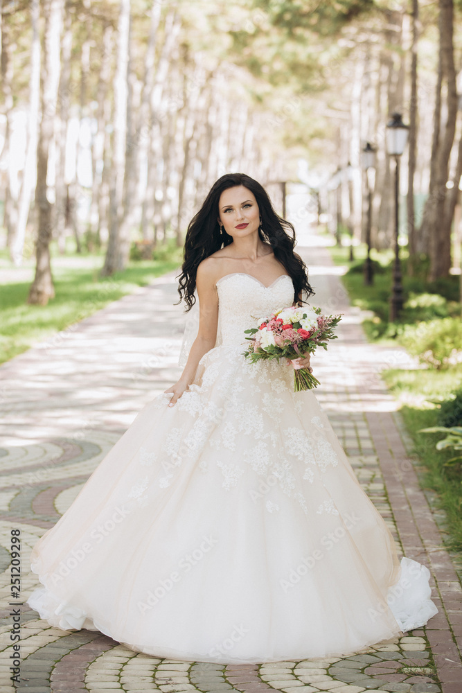 Beautiful bride in a white wedding dress on outdoors. Holding a wedding bouquet Beautiful bride in a white wedding dress on outdoors. Holding a wedding bouquet