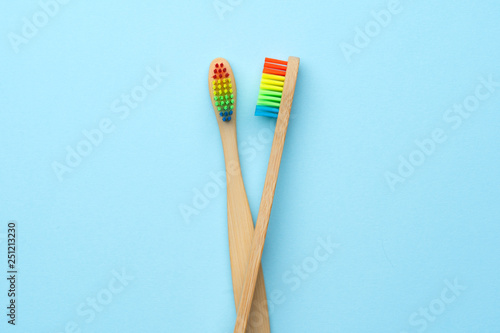 Photo of two wooden toothbrushes with rainbow-colored bristles .