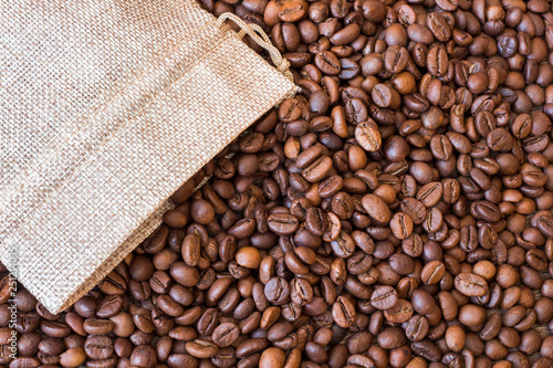 Coffee grains scatter out of the bag. The background of coffee beans_ © Volodymyr