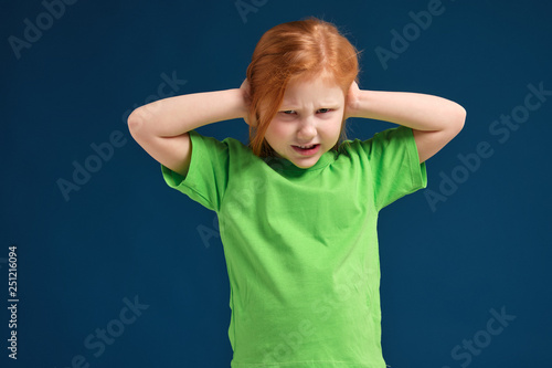 close up photo of little redhead emotional girl posing before camera on blue background
