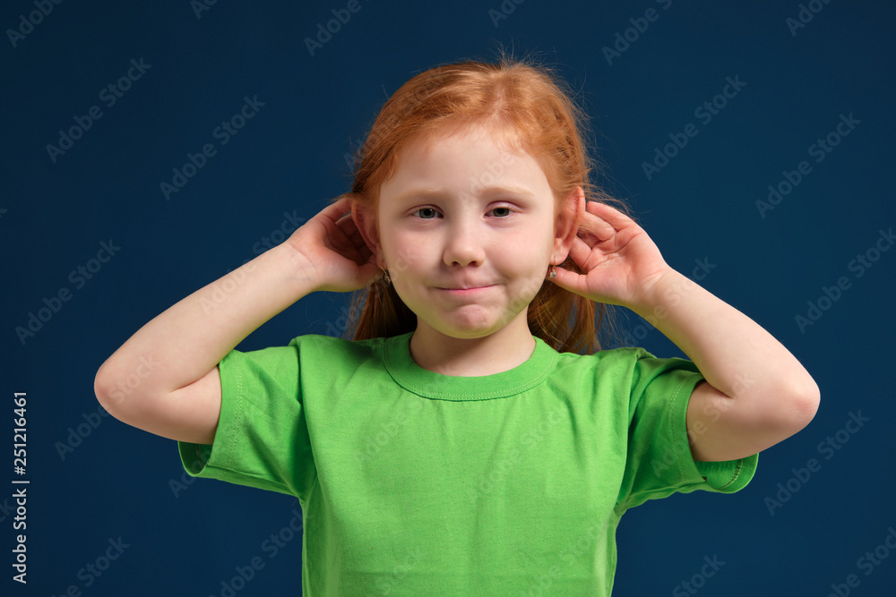 close up photo of little redhead emotional girl posing before camera on blue background