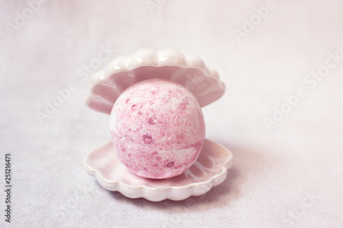 Spa still life, pink bath bomb in sea shell on white background