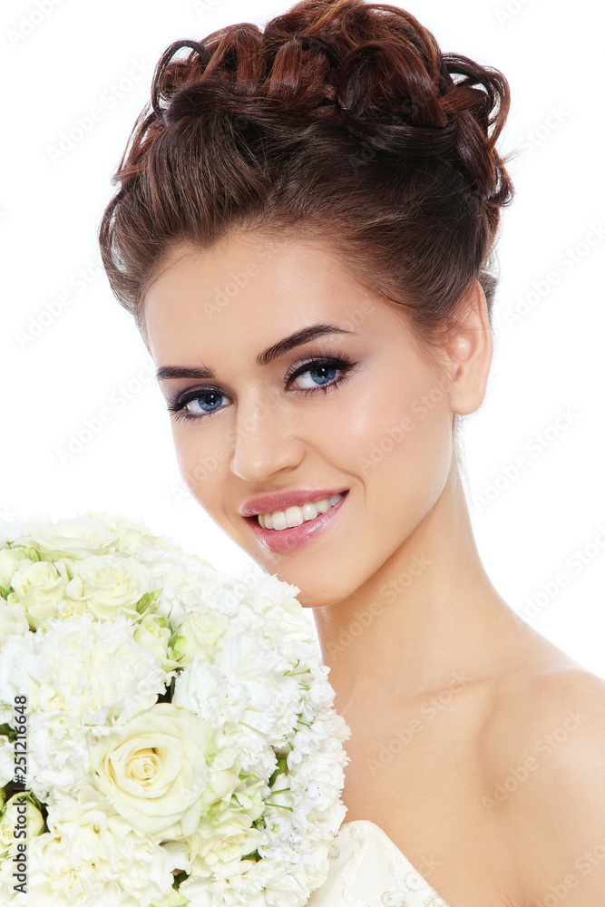 Young beautiful happy bride with winged eye make-up and prom hairdo holding fancy bouquet in her hand Young beautiful happy bride with winged eye make-up and prom hairdo holding fancy bouquet in her hand