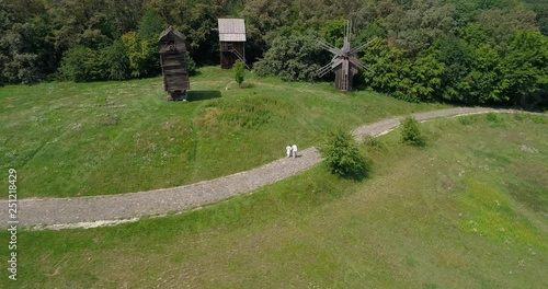 Wallpaper Mural  People walk along the stone road in the Museum of National Architecture and Life of Ukraine in the village of Pirogovo. Aerial view. Wooden windmills. Flying over the green field. Summer. 4K footage Torontodigital.ca