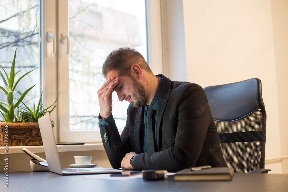 businessman working on laptop in office headache by window black table with notebook papers phone migraine businessman working on laptop in office headache by window black table with notebook papers phone migraine