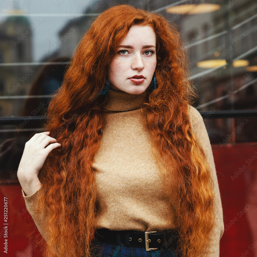 Outdoor portrait of young beautiful redhead lady with natural long curly  hair and feckles wearing beige turtleneck sweater, posing in street Stock  Photo | Adobe Stock
