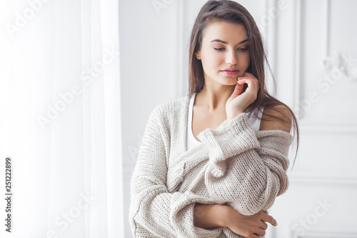 Attractive young woman indoor portrait. Female wearing casual clothes. Beautiful lady at home on neutral background. Female looking at camera.