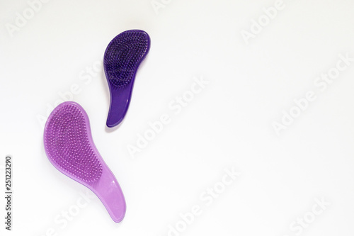 Two plastic brashes of purple color for making hairstyle and combing hair on white background with copyspace.