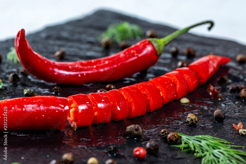 Fresh chili Pepper spicy with spices and herbs on black stone background. The concept of cooking food, the ingredients of the dish. The view from the top. Flatley