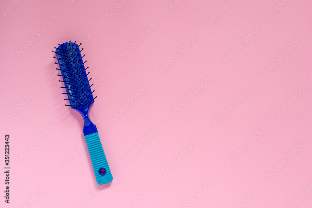 Blue plastic hair for combing hair on pink background with copyspace. - obrazy, fototapety, plakaty 