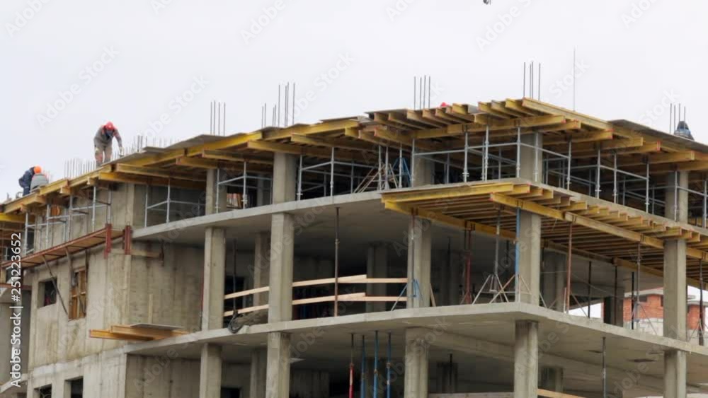 Work on the construction site. Builders work on the top of the building of concrete. Work on the construction site. Builders work on the top of the building of concrete.
