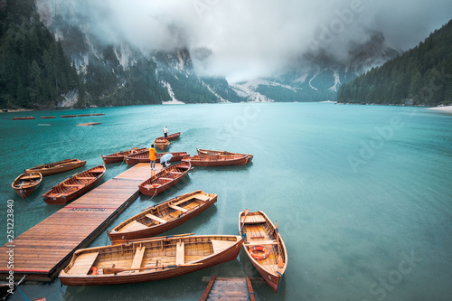 Amazing view of Lago di Braies (Braies lake, Pragser wildsee) in clouds and rain. Trentino Alto Adidge, Dolomites mountains, South Tyrol, Italy. Boats at the lake. Fanes-Sennes-Braies national park. photo