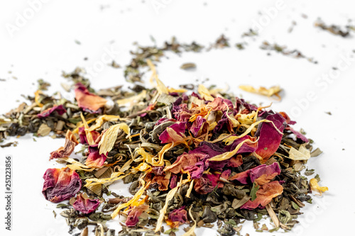 Green tea with dried flower petals and pieces of citrus on white background. Dried tea for welding. Diet and healthy drink