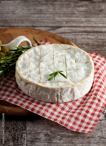 Brie type of cheese. Camembert cheese. Fresh Brie cheese and a slice on a wooden board with nuts, honey and leaves. Italian, French cheese.