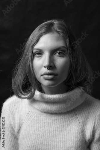 Black and white fashion portrait of beautiful girl with curly hair and big lips in white sweater posing in studio in front of black background. Art photo portrait