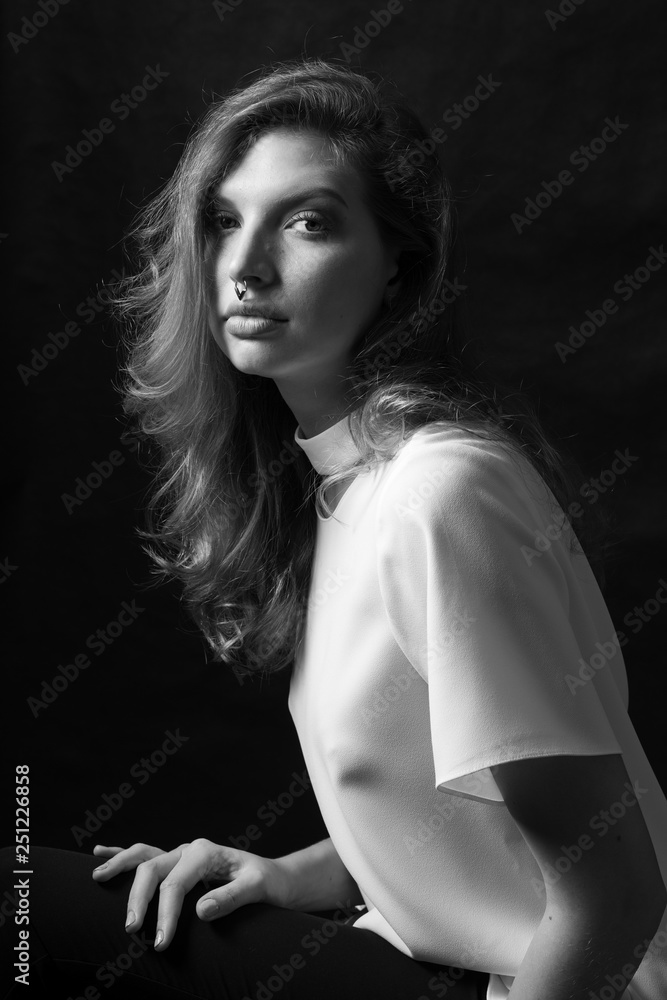 Black and white fashion portrait of beautiful model woman with luxurious curly hair in elegant white blouse posing in studio in front of black background. Art photo portrait Black and white fashion portrait of beautiful model woman with luxurious curly hair in elegant white blouse posing in studio in front of black background. Art photo portrait