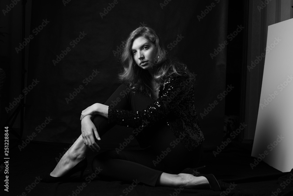 Black and white fashion photo of beautiful sexy woman with luxurious curly hair in elegant jacket with rhinestones posing in studio in front of black backgroung. Full-length girl model Black and white fashion photo of beautiful sexy woman with luxurious curly hair in elegant jacket with rhinestones posing in studio in front of black backgroung. Full-length girl model