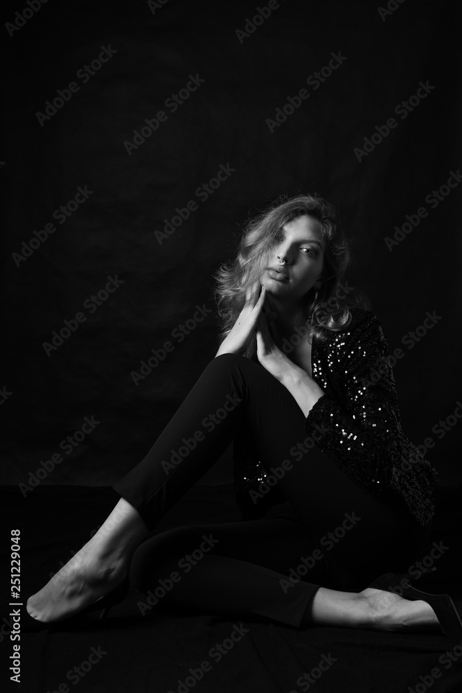 Black and white fashion photo of beautiful sexy woman with luxurious curly hair in elegant jacket with rhinestones posing in studio in front of black backgroung. Full-length girl model Black and white fashion photo of beautiful sexy woman with luxurious curly hair in elegant jacket with rhinestones posing in studio in front of black backgroung. Full-length girl model