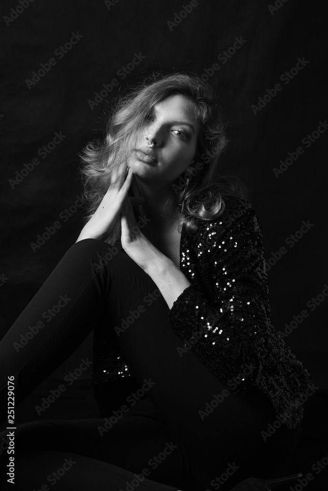 Black and white fashion photo of beautiful sexy woman with luxurious curly hair in elegant jacket with rhinestones posing in studio in front of black backgroung. Full-length girl model Black and white fashion photo of beautiful sexy woman with luxurious curly hair in elegant jacket with rhinestones posing in studio in front of black backgroung. Full-length girl model