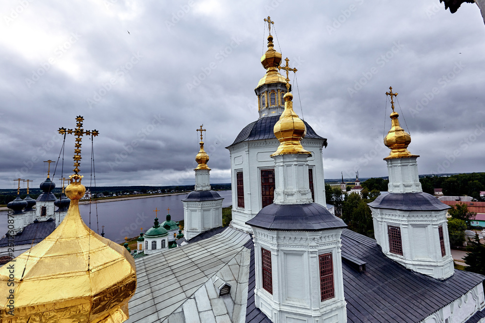 Eastern orthodox crosses on gold domes, cupolas, against blue sky with clouds