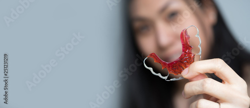 Portrait of beautiful Asian patient woman holding orthodontic retainers in dental clinic, Smiling Girl Holding blue Retainer, Braces for Teeth. Orthodontics Dental Theme, Methods of Teeth Correction