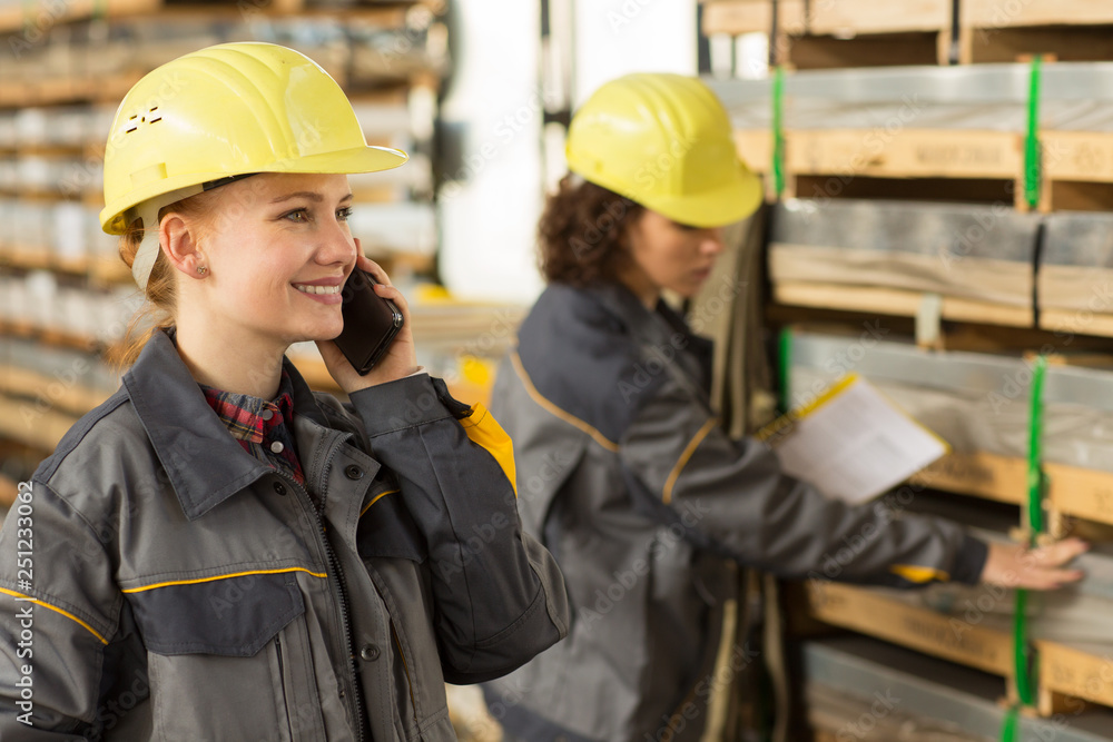 Female worker speaking on mobile phone while her colleague checking shelves. Female worker speaking on mobile phone while her colleague checking shelves.