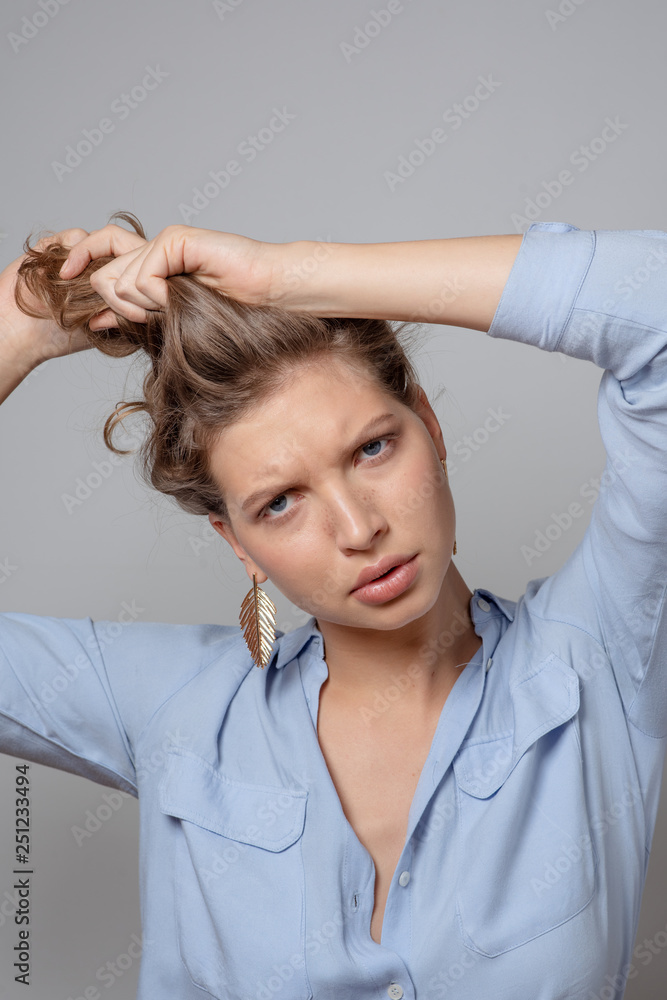 Beautiful nervous young woman collect hair in a ponytail. Healthy curly hair. Matted hair concept. Studio shot Beautiful nervous young woman collect hair in a ponytail. Healthy curly hair. Matted hair concept. Studio shot