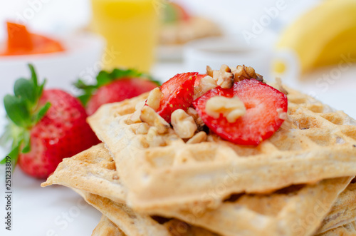Desayuno saludable - waffles de harina del negrito, servidos con nueces, fresas y jugo fresco