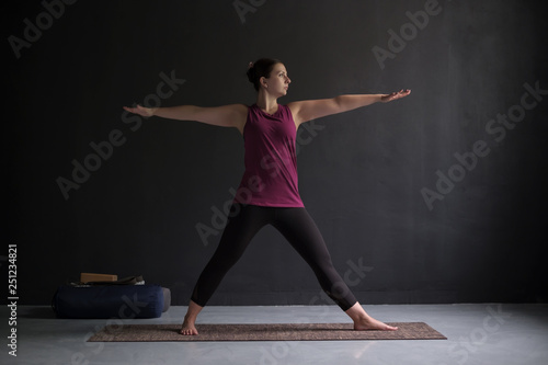 Attractive young woman working out indoors doing yoga exercise