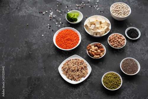 Superfoods on a gray background with copy space. Nuts, beans, greens and seeds. Healthy vegan food