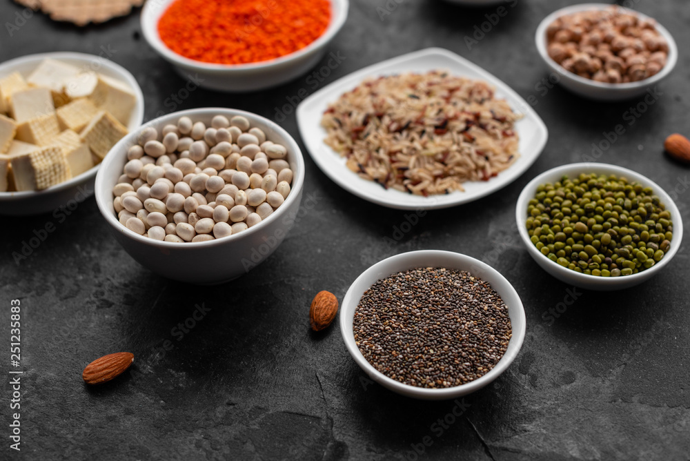 Superfoods on a gray background with copy space. Nuts, beans, greens and seeds. Healthy vegan food