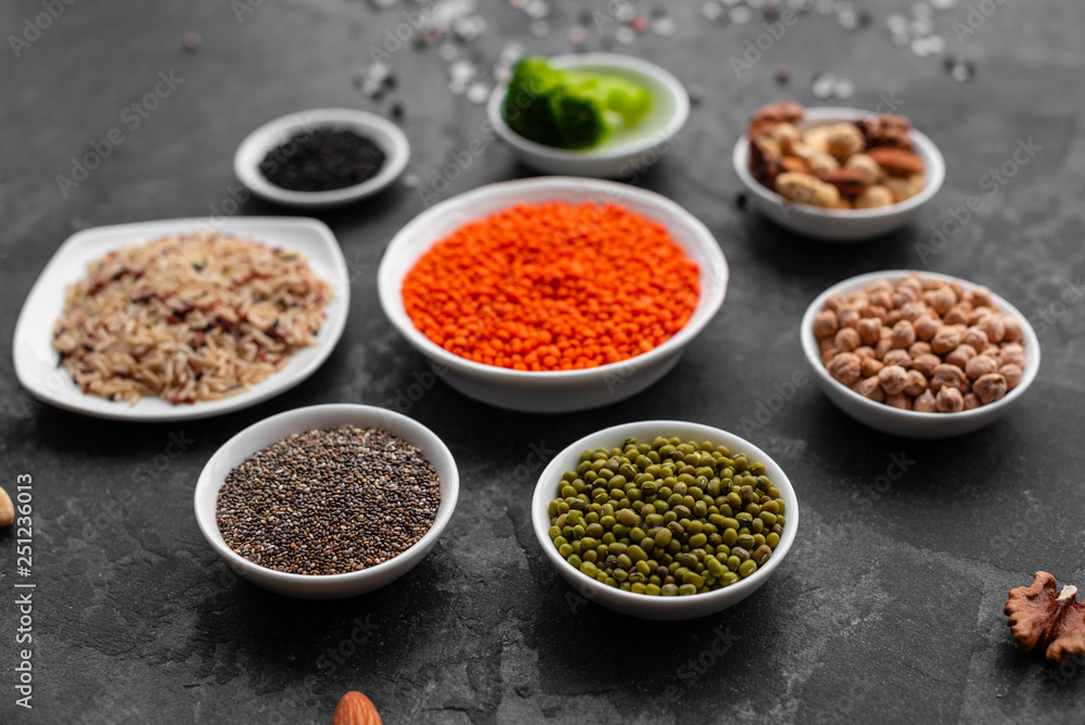 Superfoods on a gray background with copy space. Nuts, beans, greens and seeds. Healthy vegan food