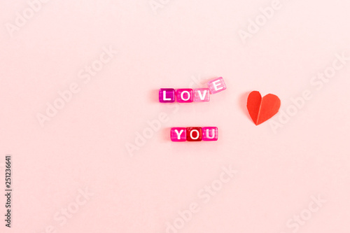 Love you inscription made of colorful cube beads with letters. Festive pink background concept with copy space