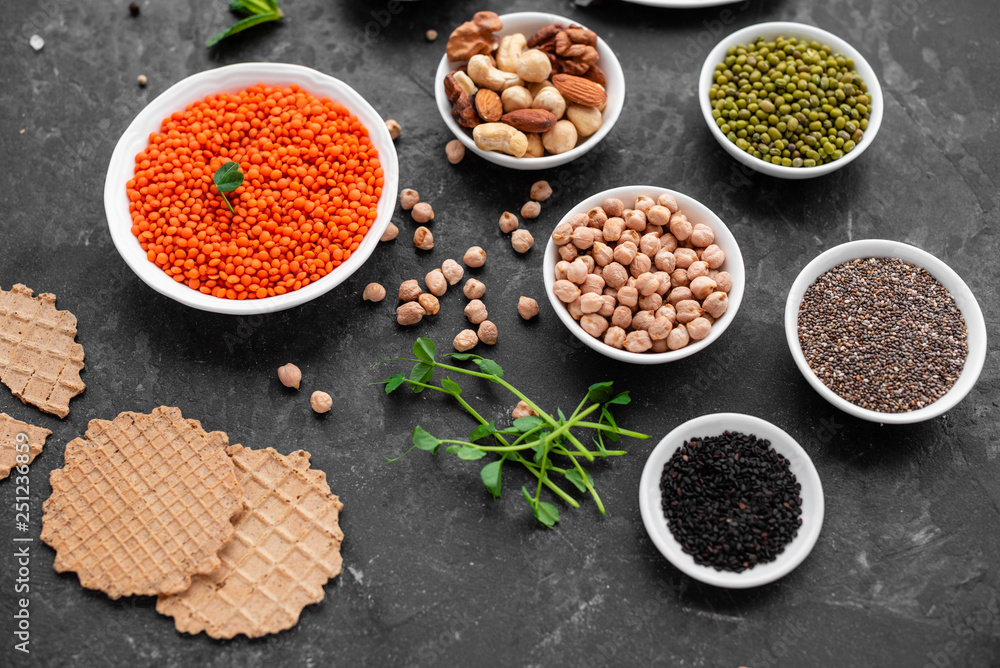 Superfoods on a gray background with copy space. Nuts, beans, greens and seeds. Healthy vegan food