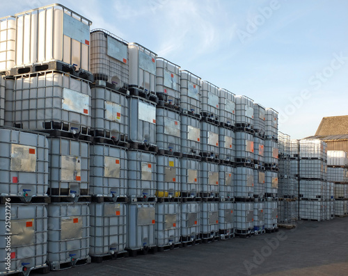 used metal framed intermediate bulk containers stacked on pallets waiting to be cleaned or recycled in an industrial yard photo