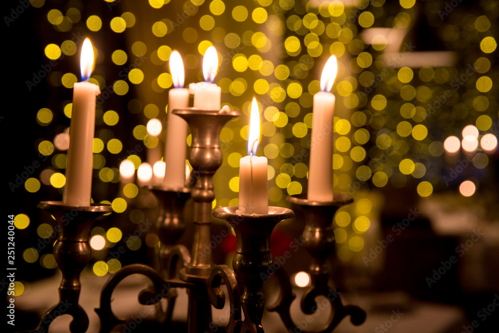 Candles to a beautiful candlestick. Candles lighting in the dark night with bulbs lights in blur Candles to a beautiful candlestick. Candles lighting in the dark night with bulbs lights in blur