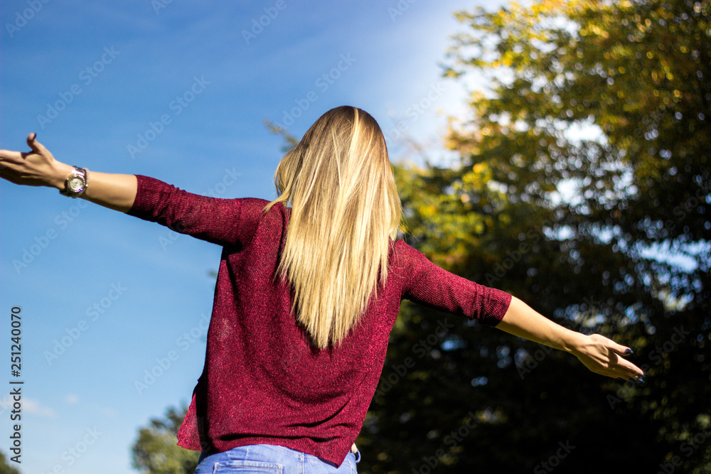 Cheerful young woman with hands raised towards sky Cheerful young woman with hands raised towards sky