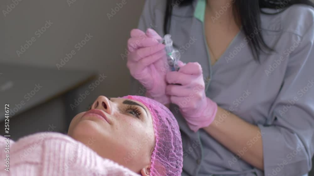 doctor cosmetologist makes Rejuvenating facial injections procedure for tightening and smoothing wrinkles on face skin of beautiful, young woman in beauty salon. Cosmetology skin care doctor cosmetologist makes Rejuvenating facial injections procedure for tightening and smoothing wrinkles on face skin of beautiful, young woman in beauty salon. Cosmetology skin care