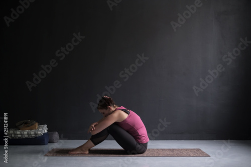 Young woman working out against blackwall, doing yoga or pilates exercise © Viktor Koldunov